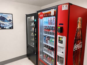 Ein Getränkeautomat mit Coca-Cola-Logo, einem digitalen Bezahlschirm und einer Auswahl an Getränken.