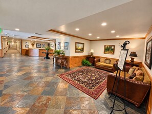 A hotel lobby with a reception desk, a patterned rug, a sofa, and artwork on the walls.