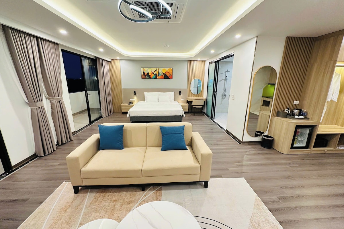 Una habitación de hotel moderna con sofá, cama, escritorio y baño.