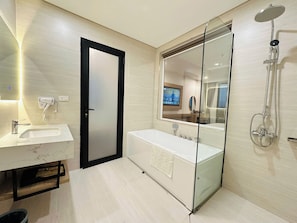 Un baño moderno con cabina de ducha de vidrio, un espejo grande y un tocador con lavabo.