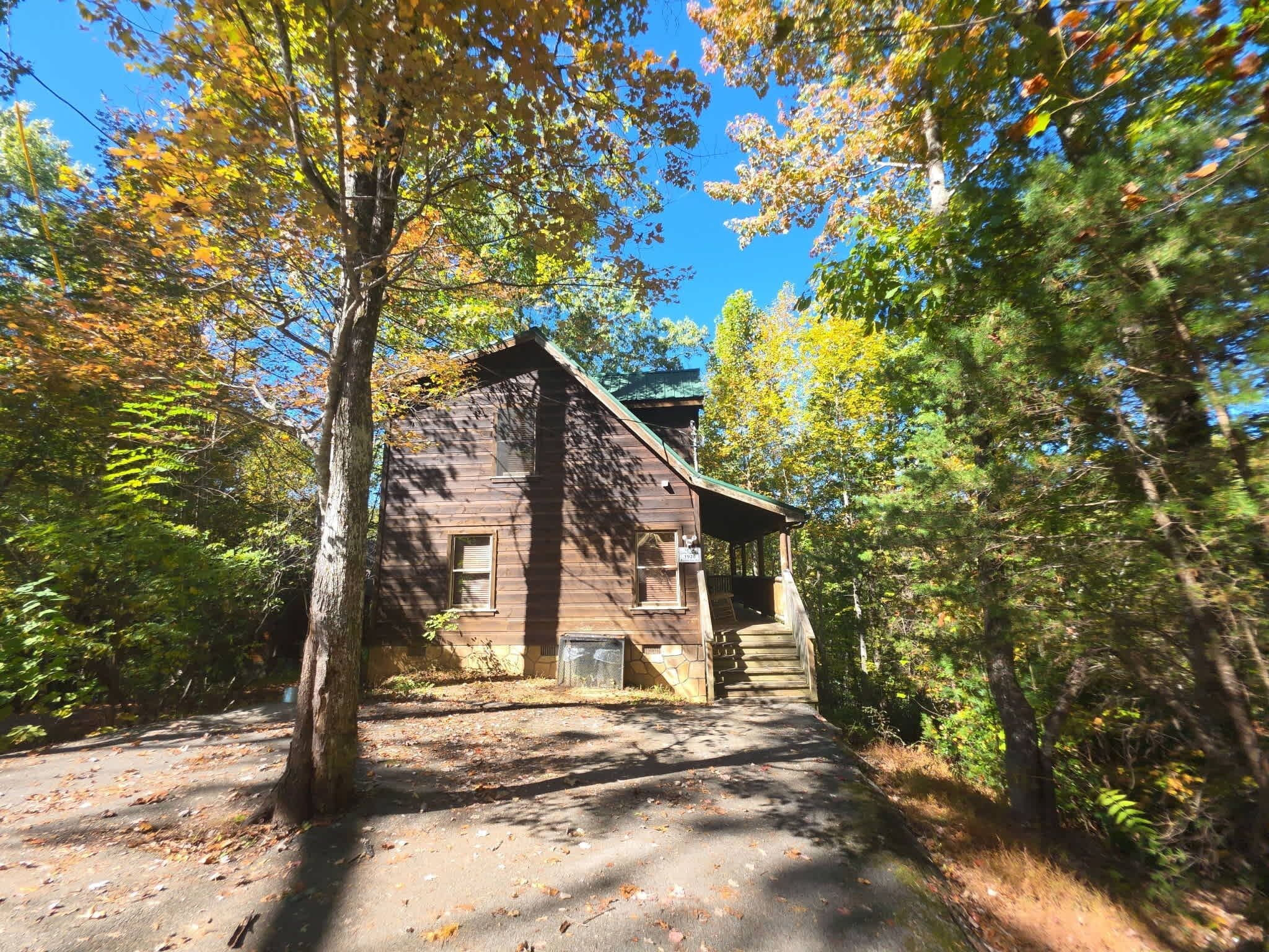 Une cabane rustique avec une façade en bois, des fondations en pierre et une véranda accessible par des marches.