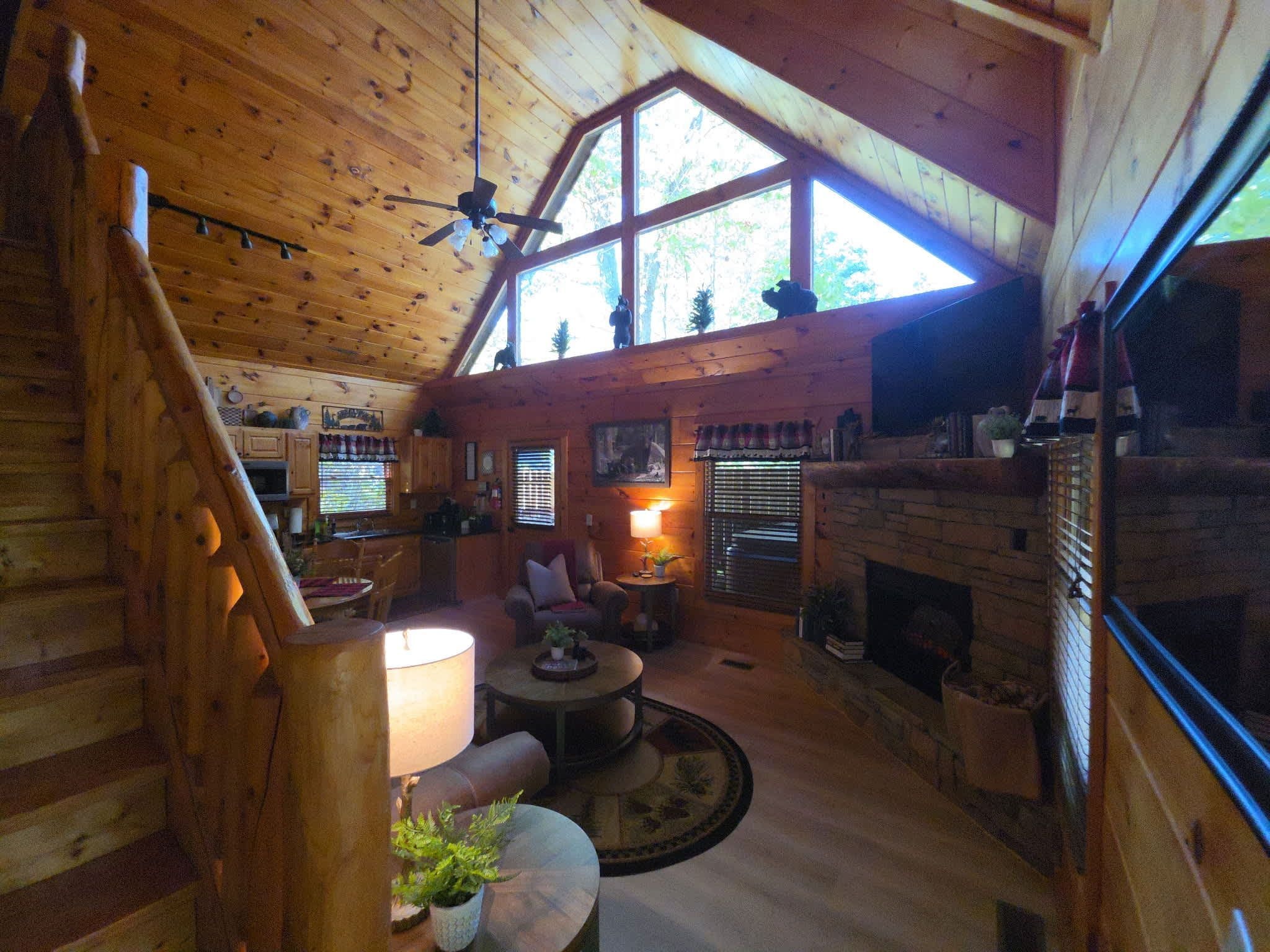 L’intérieur d’une cabane comprend une chambre à coucher située en mezzanine, une cheminée, un coin repas et un salon doté d’une grande fenêtre.