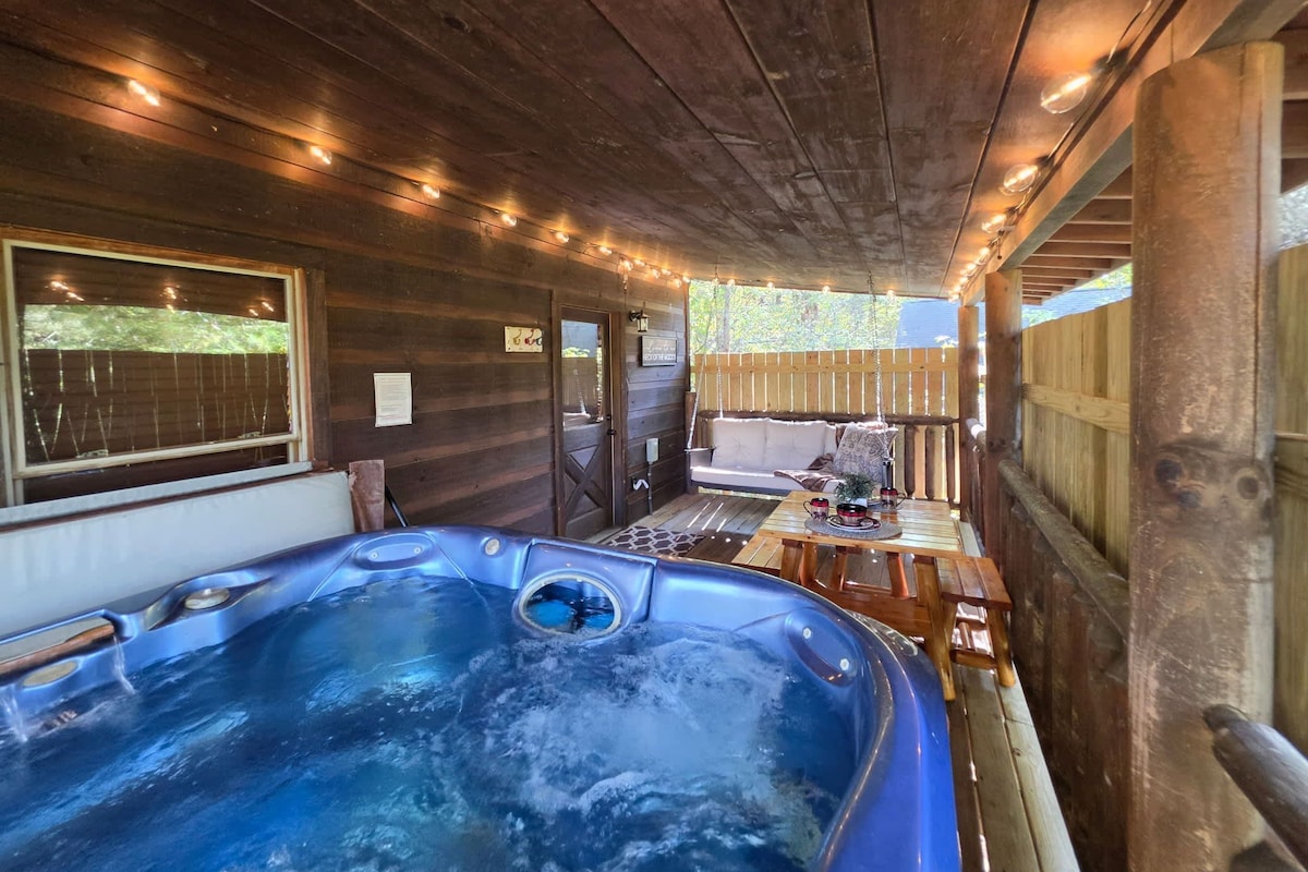 A wooden cabin interior with a hot tub, a wooden deck, and string lights.