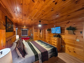 A cozy cabin-style room with a bed, a television, and a small window. - Hot Tub-fireplace-pool Table-arcade-private-relax (Sevierville)