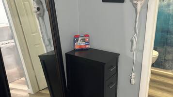 Une pièce comprenant une commode noire, un miroir, une trousse de premiers secours, un panneau indiquant la présence d’une connexion Wi-Fi et un sèche-cheveux.
