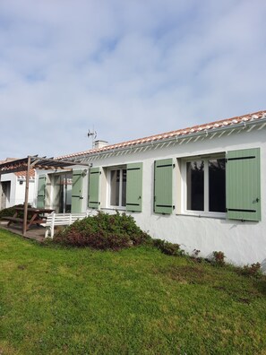 Fileira de edifícios brancos com persianas verdes, um banco de madeira e uma mesa de piquenique.