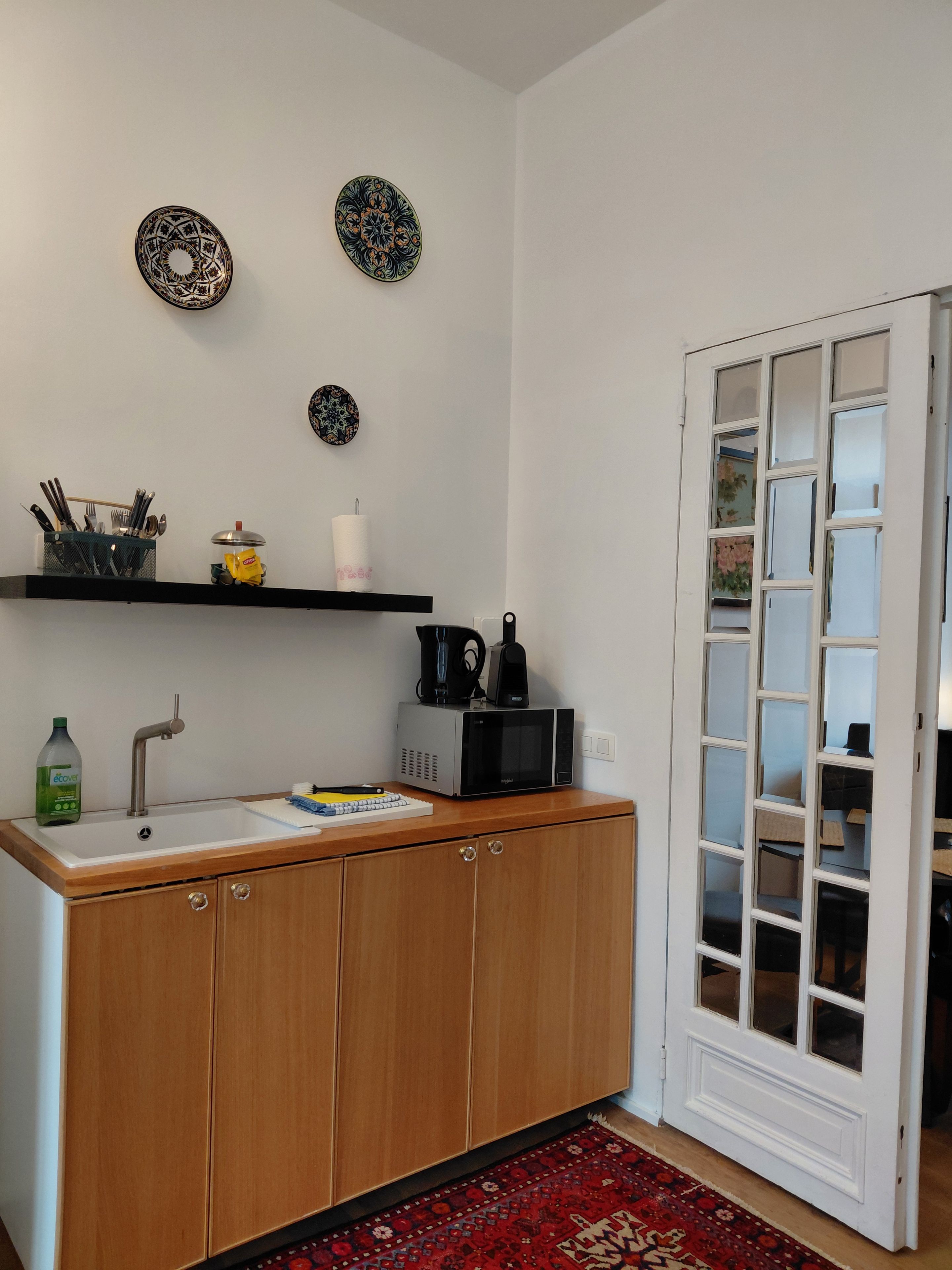 A compact kitchen with a sink, microwave, and storage cabinets.