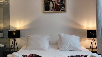 A hotel room with a bed, two bedside lamps, a painting on the wall, and a large mirror.