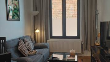 A living room with a sofa, coffee table, and a large window with curtains.
