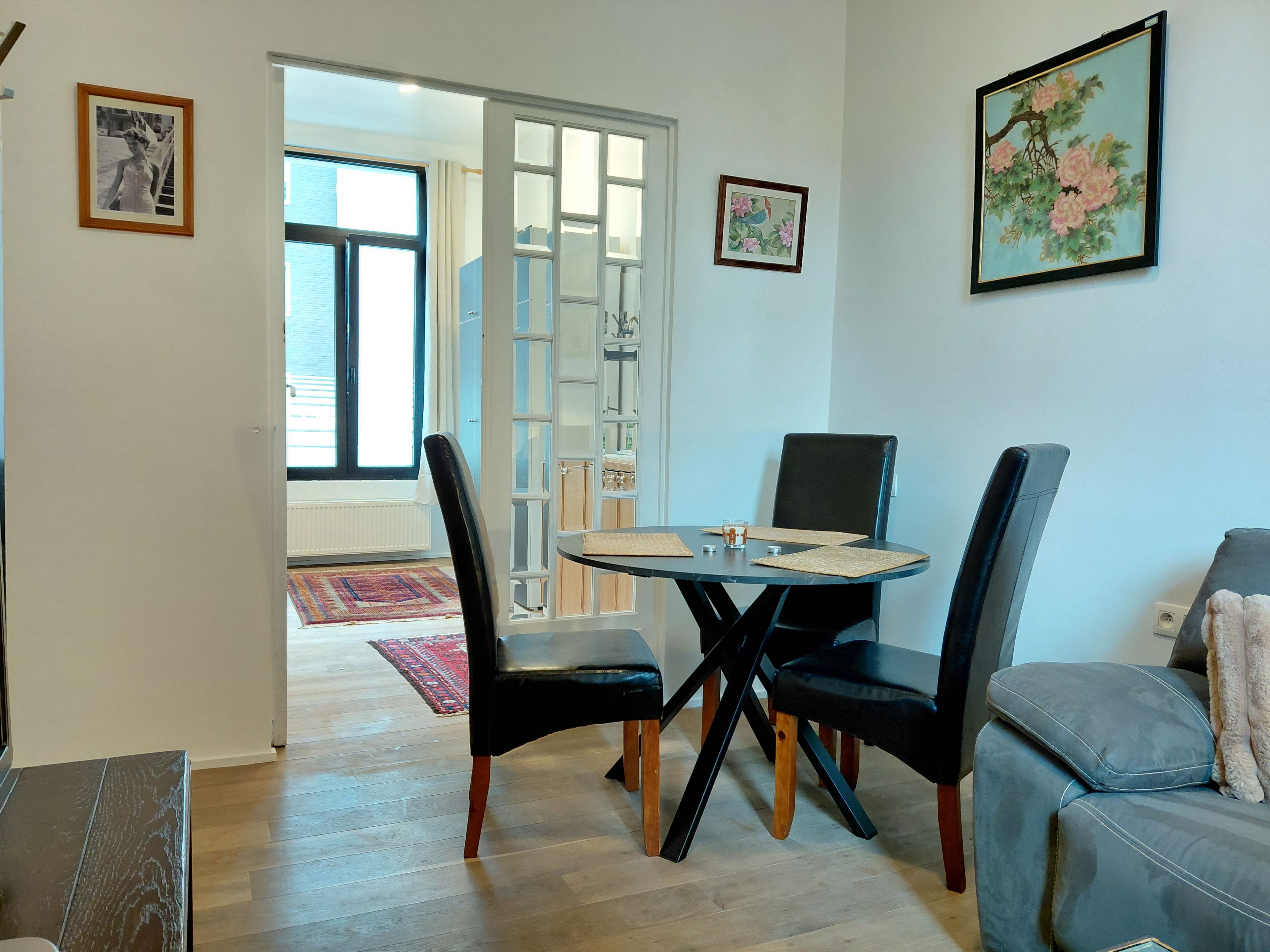 A dining area with a table, chairs, and a view through an open door.