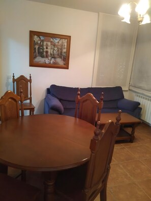 A dining area with a round wooden table and chairs, a blue sofa, and a framed picture on the wall. - Country House 'Del Maestro II' with Shared Garden (Navalosa)