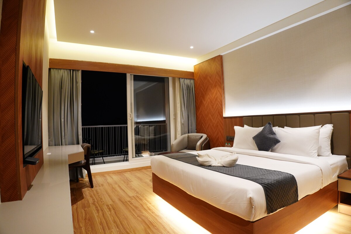 A hotel room with a large bed, a desk, and a view of the outside.
