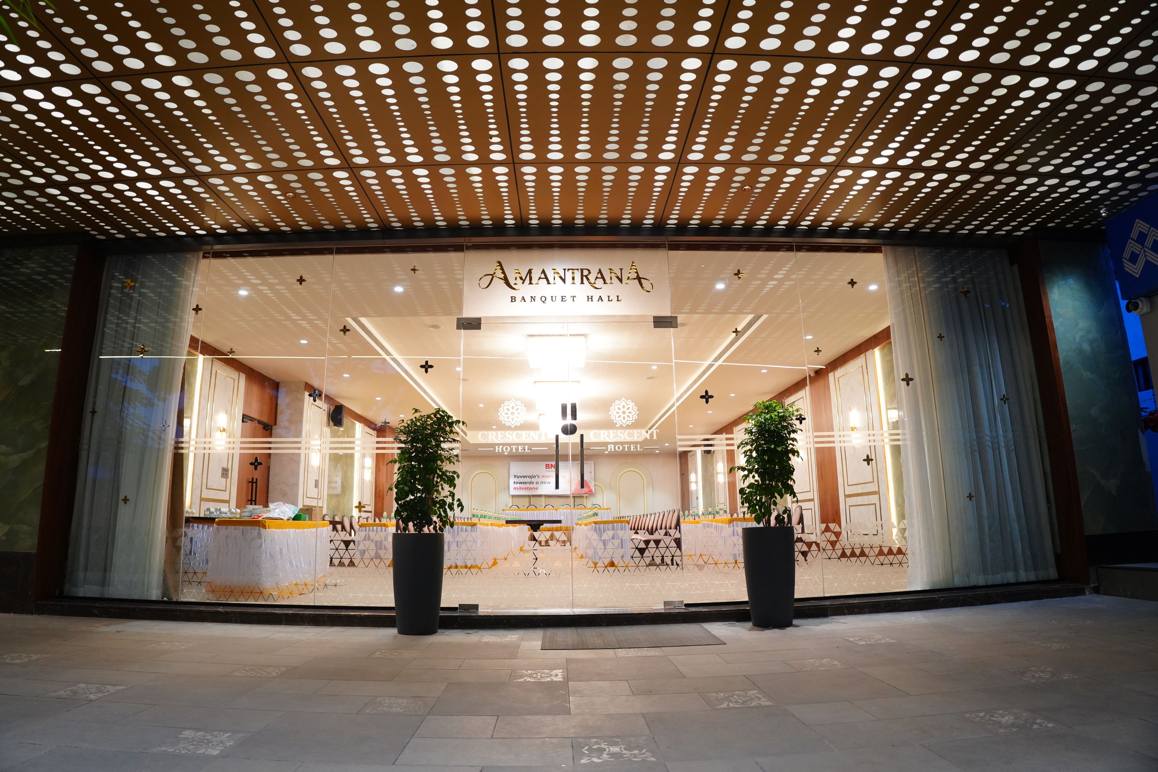 De ingang van een hotel met een modern ontwerp, met een groot bord voor de 'Amantana Banquet Hall' en 'Crescent Hotel' branding.