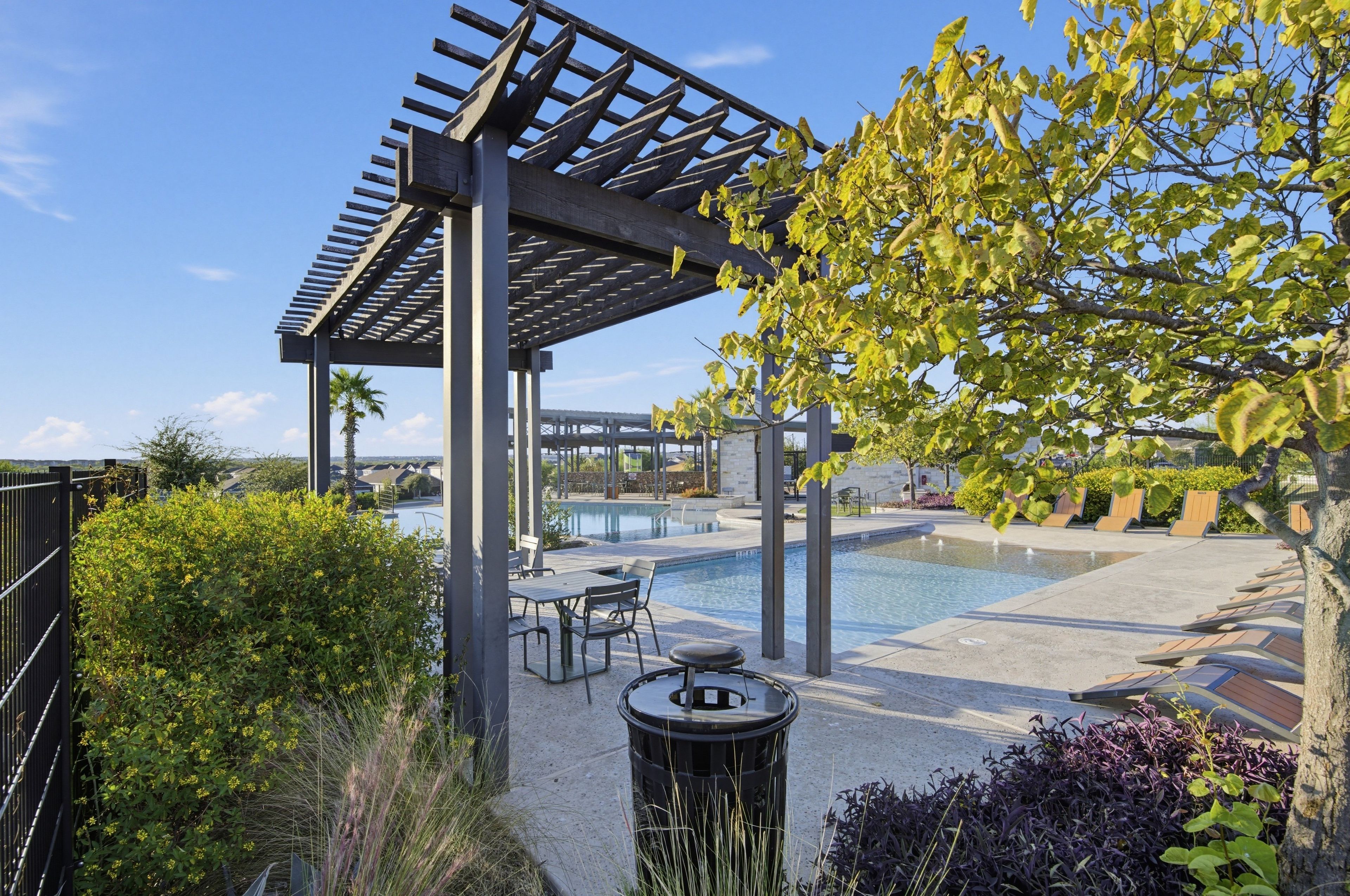 Un espacio al aire libre techado con piscina, mobiliario y una estructura de pérgola.
