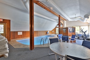 Área de piscina com hidromassagem, equipamentos de ginástica e assentos.