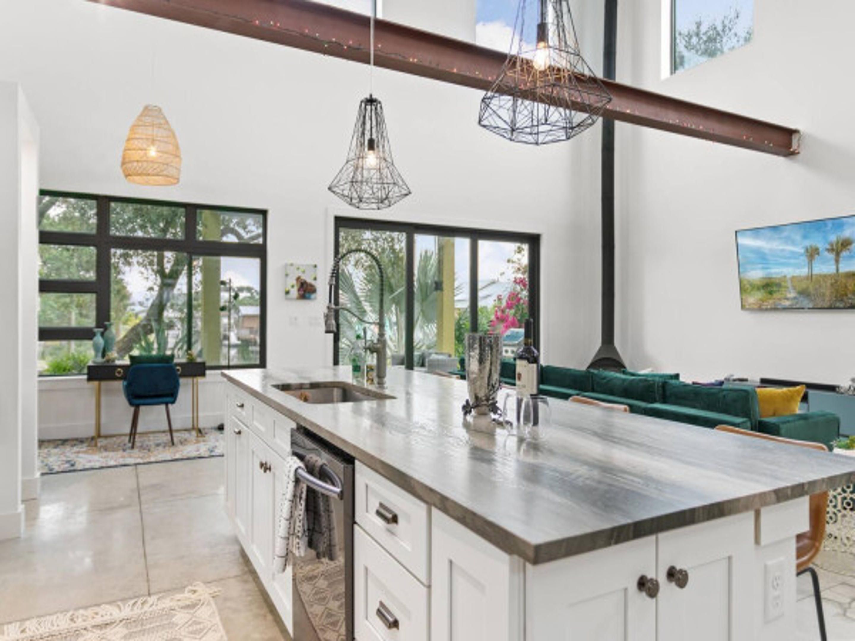 Een moderne keuken met een groot eiland, hanglampen en uitzicht op de omgeving.