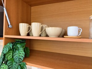 Une étagère en bois avec des tasses et des soucoupes en céramique.