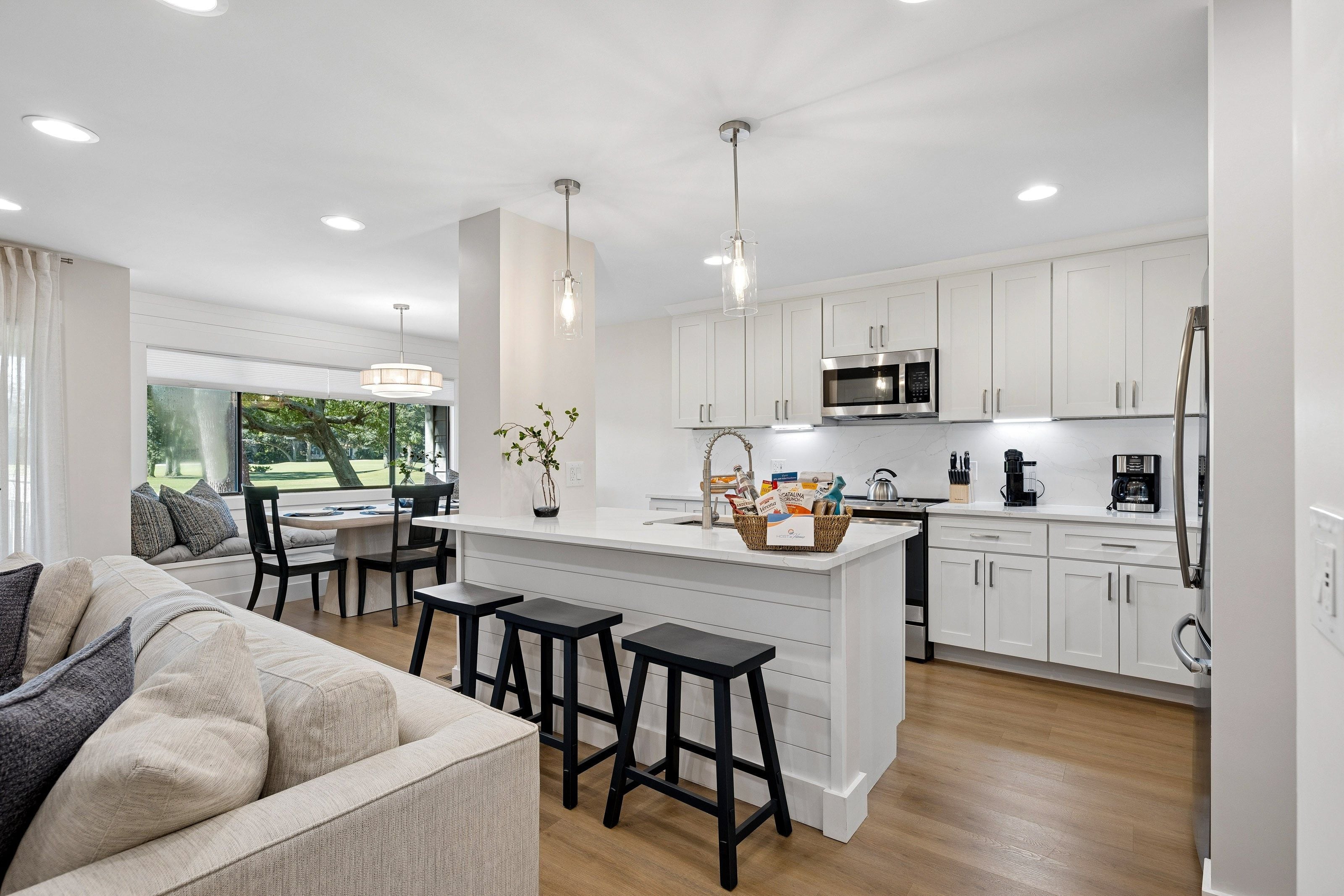 A modern kitchen with white cabinetry, a central island, and bar stools.