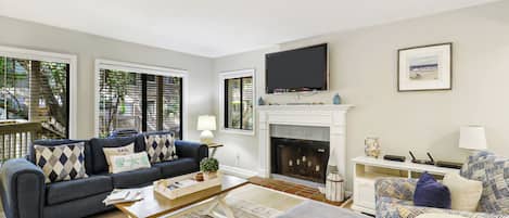 Una sala de estar con sofá, mesa de centro, chimenea y televisor.