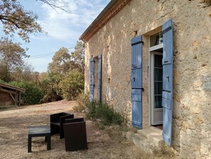 A stone building with blue shutters, a wooden bench, and a small table. - New Listing (Sainte-Gemme)