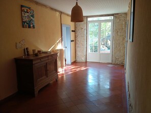 A spacious room with a wooden cabinet, a hanging light fixture, and a door leading to an outdoor area. - New Listing (Sainte-Gemme)