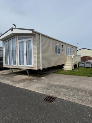 A mobile home with a front porch and a small deck.