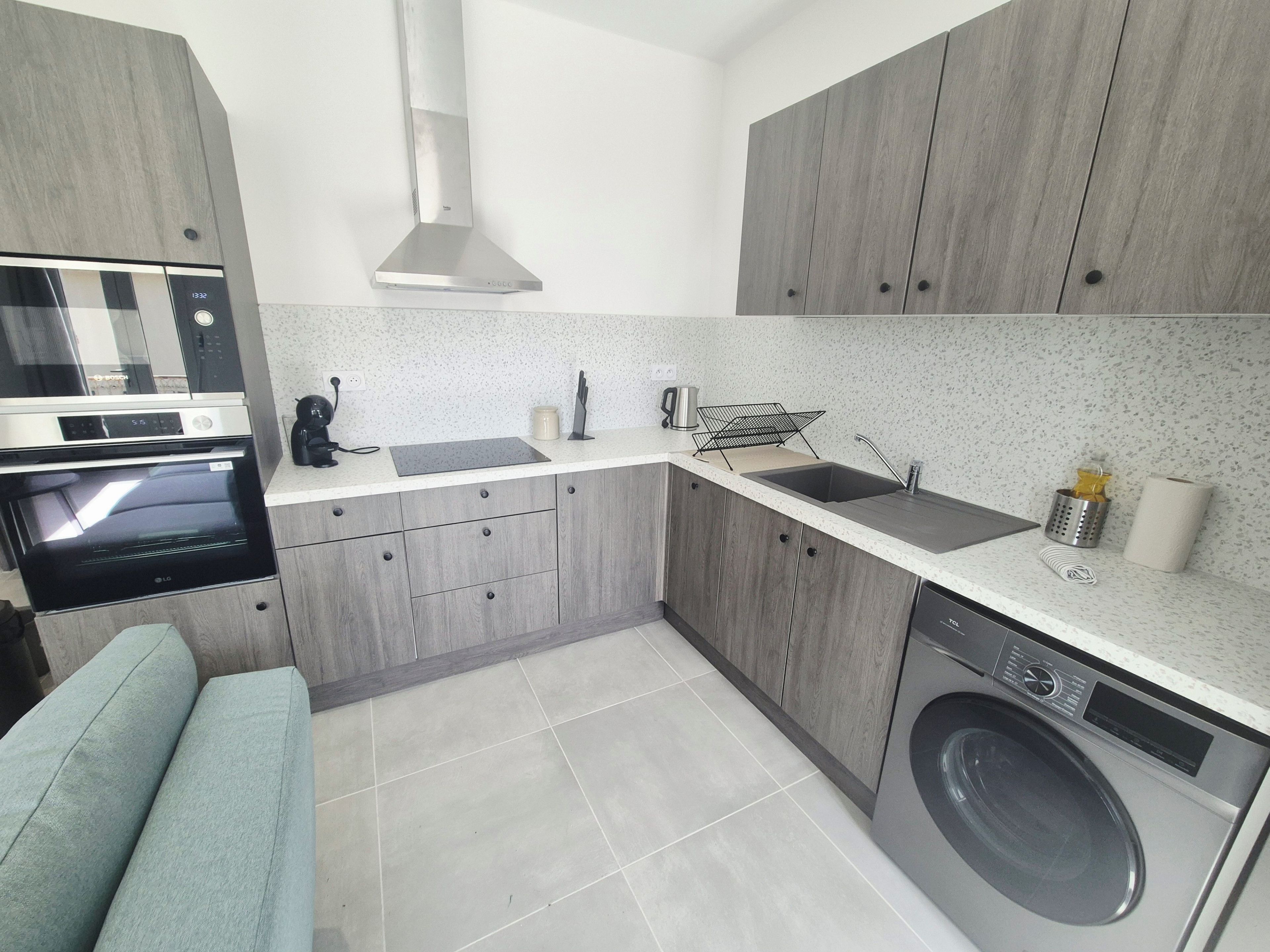 A compact kitchen with a built-in oven, microwave, and washing machine.