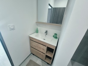 A bathroom with a white sink, a mirror, and a green soap dispenser. - Apartment with balcony near the sea, sleeps 4 (Toulon)