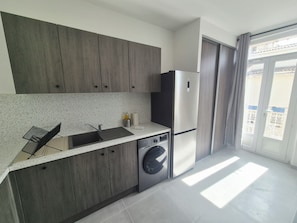 A modern kitchen with a built-in washing machine, a stainless steel refrigerator, and a window with a view. - Apartment with balcony near the sea, sleeps 4 (Toulon)