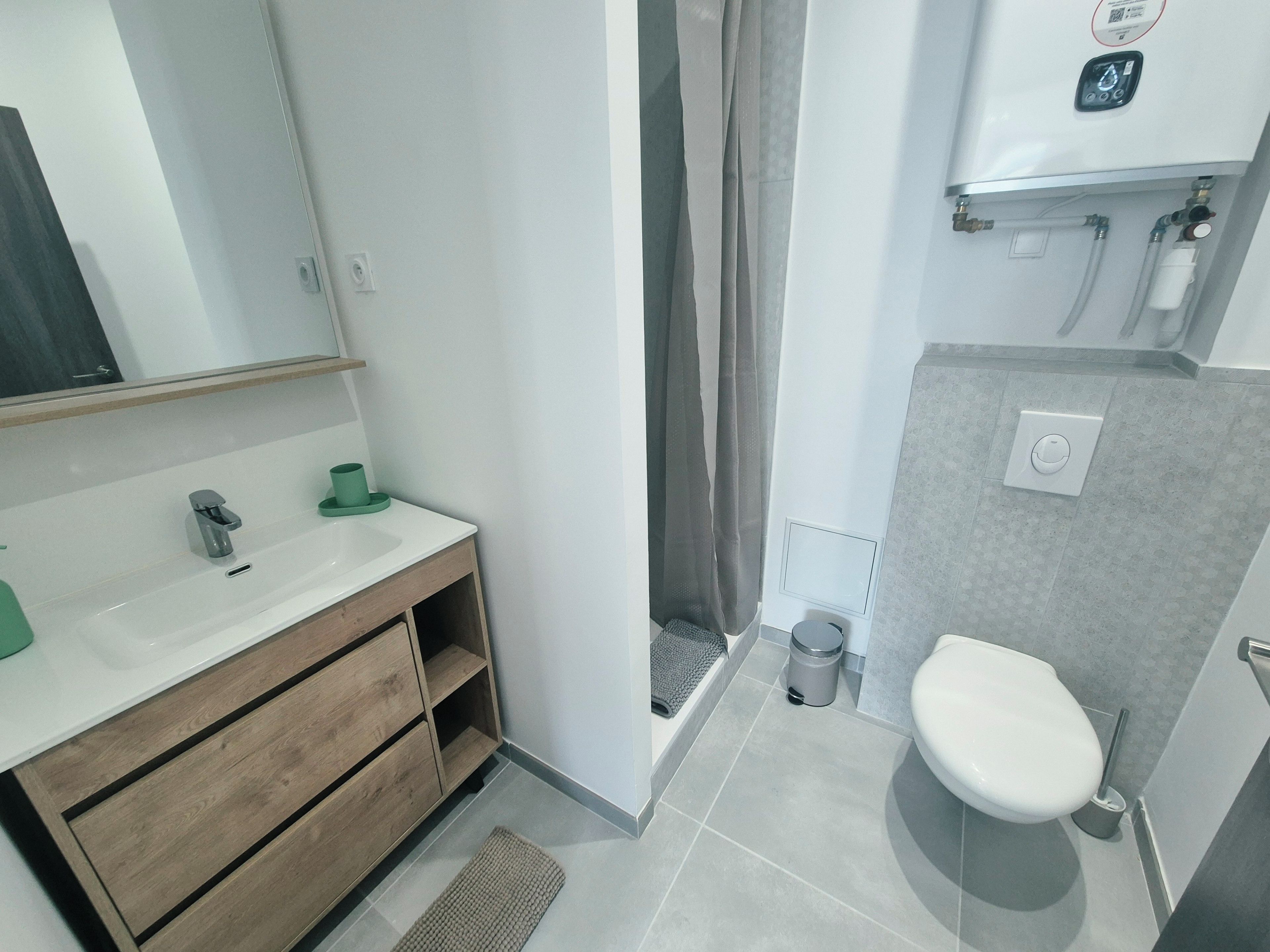 Une salle de bain comprenant des toilettes, un lavabo et un espace douche.