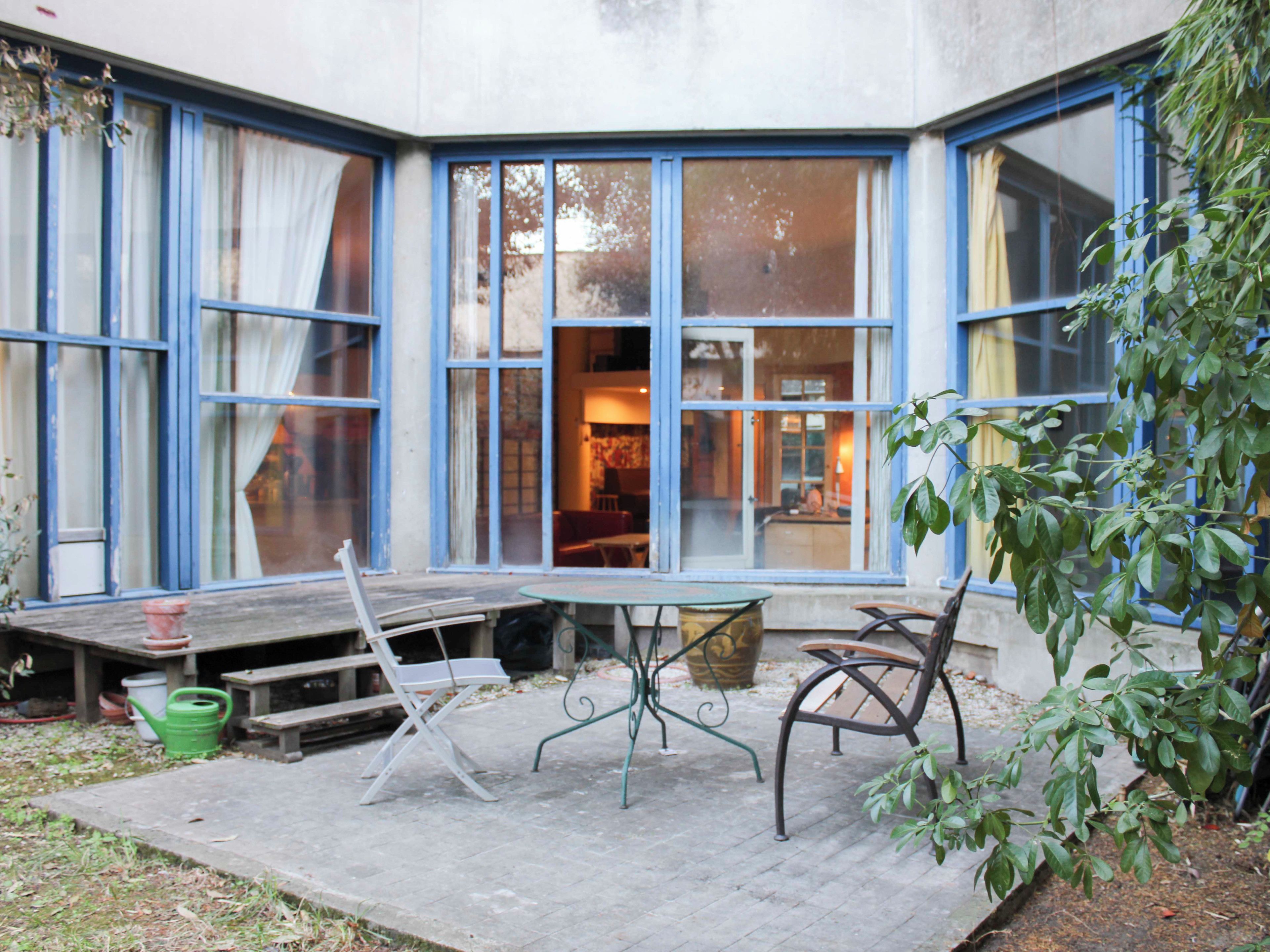 Un patio esquinero con una mesa, sillas y un banco.