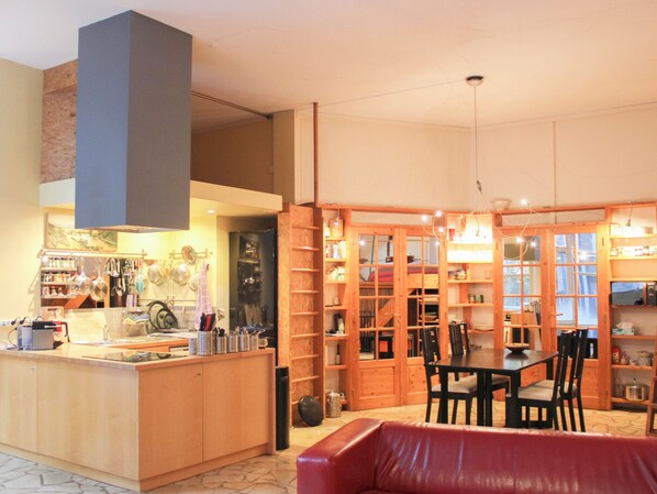 A kitchen with wooden cabinets, a dining table with chairs, and a red leather sofa. - Large, quiet apart with garden, close to transport (Ivry-sur-Seine)