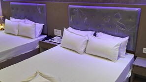Une chambre d’hôtel avec deux lits, chacun équipé de draps et d’oreillers blancs, ainsi qu’une table de chevet avec un téléphone et une tasse.