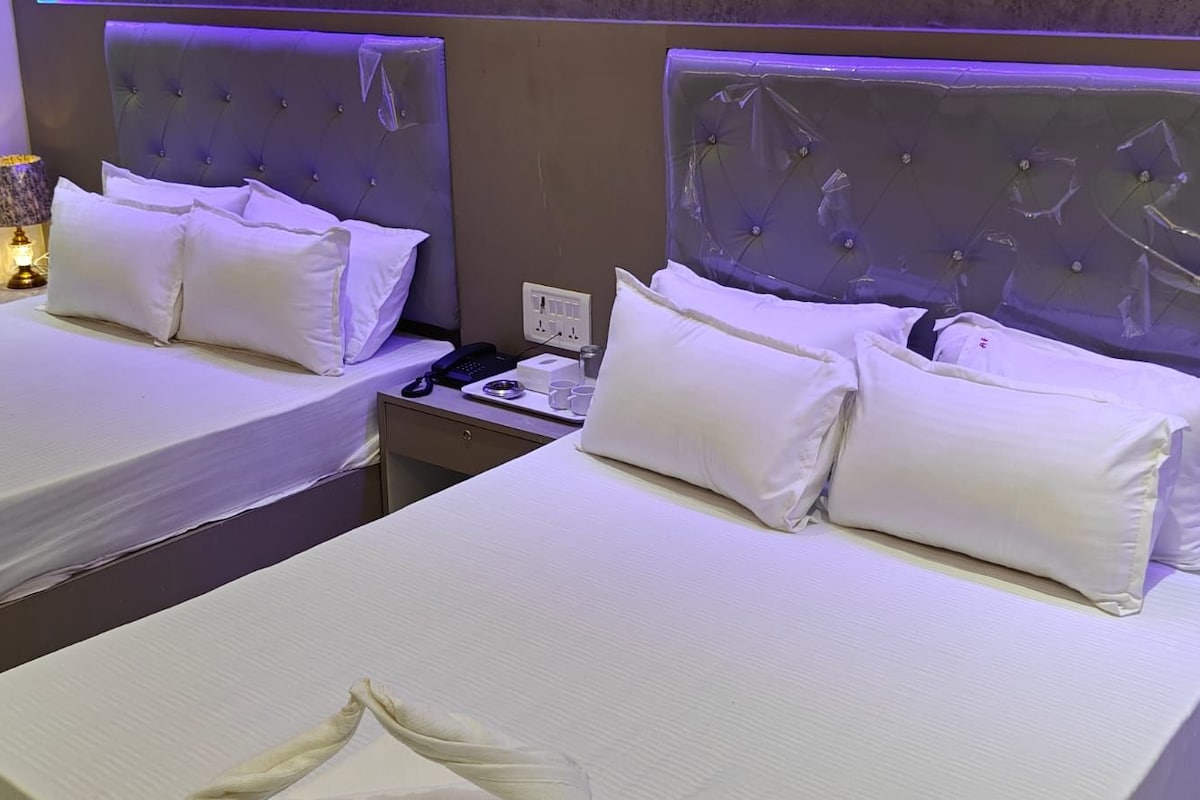 Une chambre d’hôtel avec deux lits, chacun doté de draps et d’oreillers blancs, une table de chevet avec une lampe et un téléphone fixé au mur.