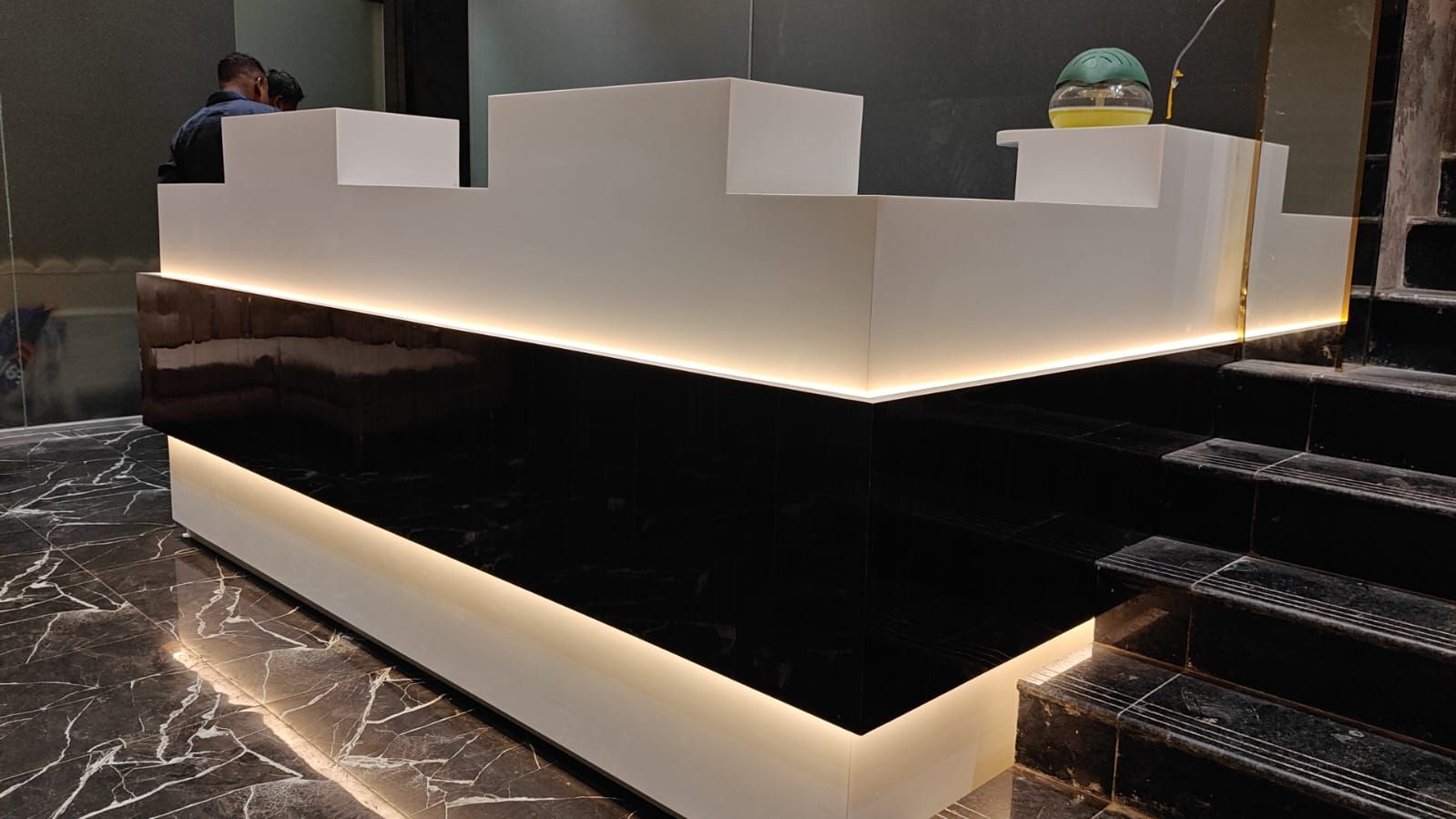 A reception desk with a black marble floor and a white counter.