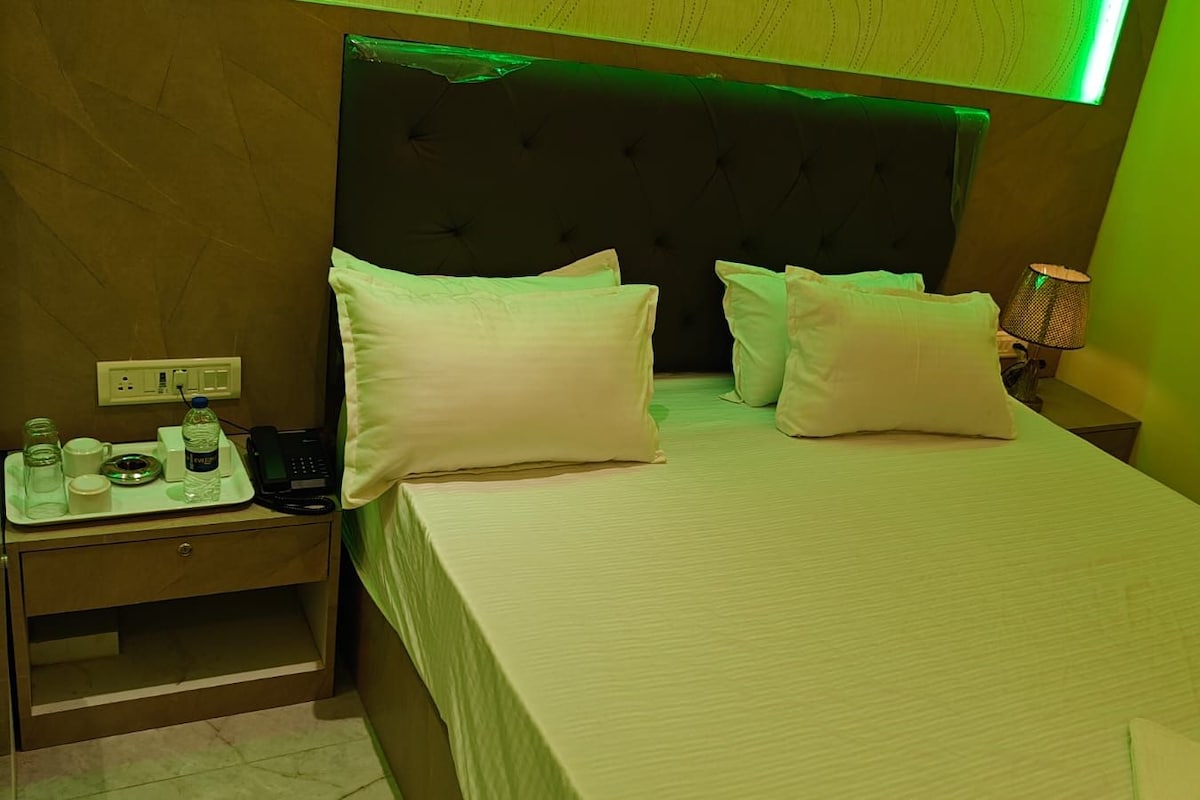 Une chambre d’hôtel avec un lit, des oreillers, une table de chevet avec un téléphone et un plateau contenant des articles de toilette.