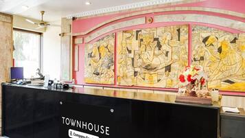 Eine Rezeption mit einem 'Townhouse'-Schild, eine Wand mit Reliefkunst und eine Decke mit Einbaustrahlern.