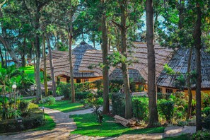 A resort with thatched-roof huts surrounded by lush greenery and a clear view of the sea. - Lakeside Escape Resort (Mukono)