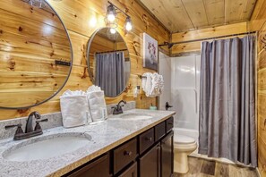 Ein Badezimmer im Stil einer Holzhütte mit einem Doppelwaschbecken, einer Toilette und einer Duschkabine.