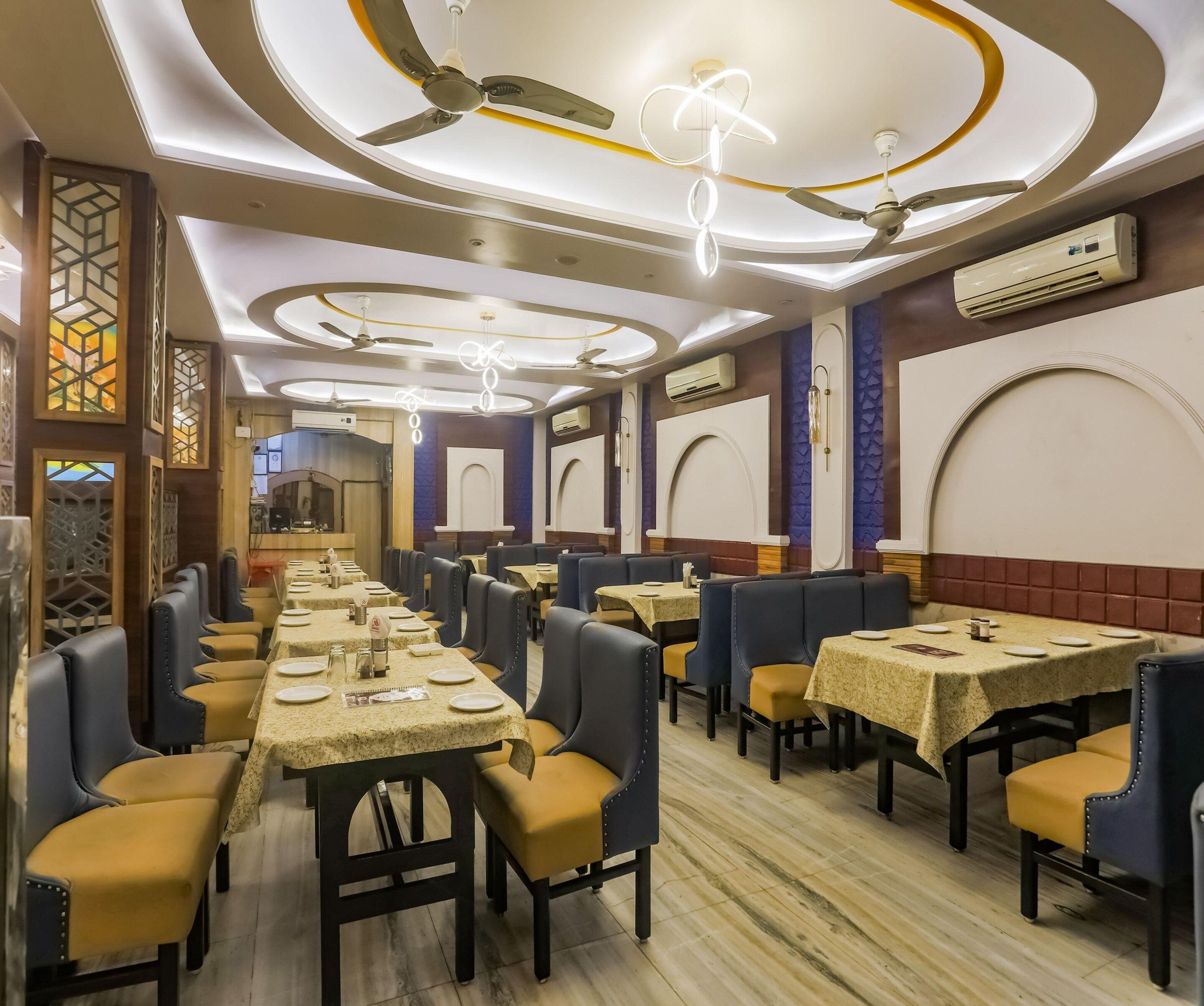 A restaurant with multiple tables and chairs, ceiling fans, and decorative lighting.
