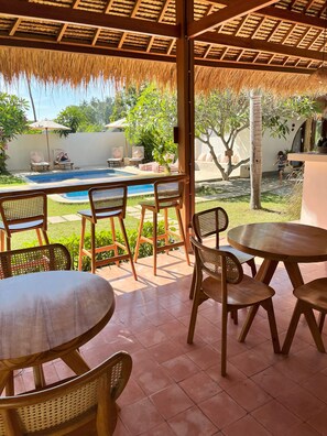 Ein überdachter Außenbereich mit Pool, Liegestühlen und einem Tisch.