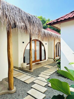 Un complexe hôtelier doté de bâtiments à toits de chaume, d’un sentier en pierre et d’un jardin tropical.