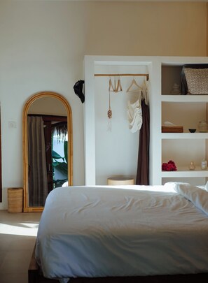Ein Schlafzimmer mit einem Bett, einem Kleiderschrank, einem Spiegel und einem Regal mit Gegenständen.