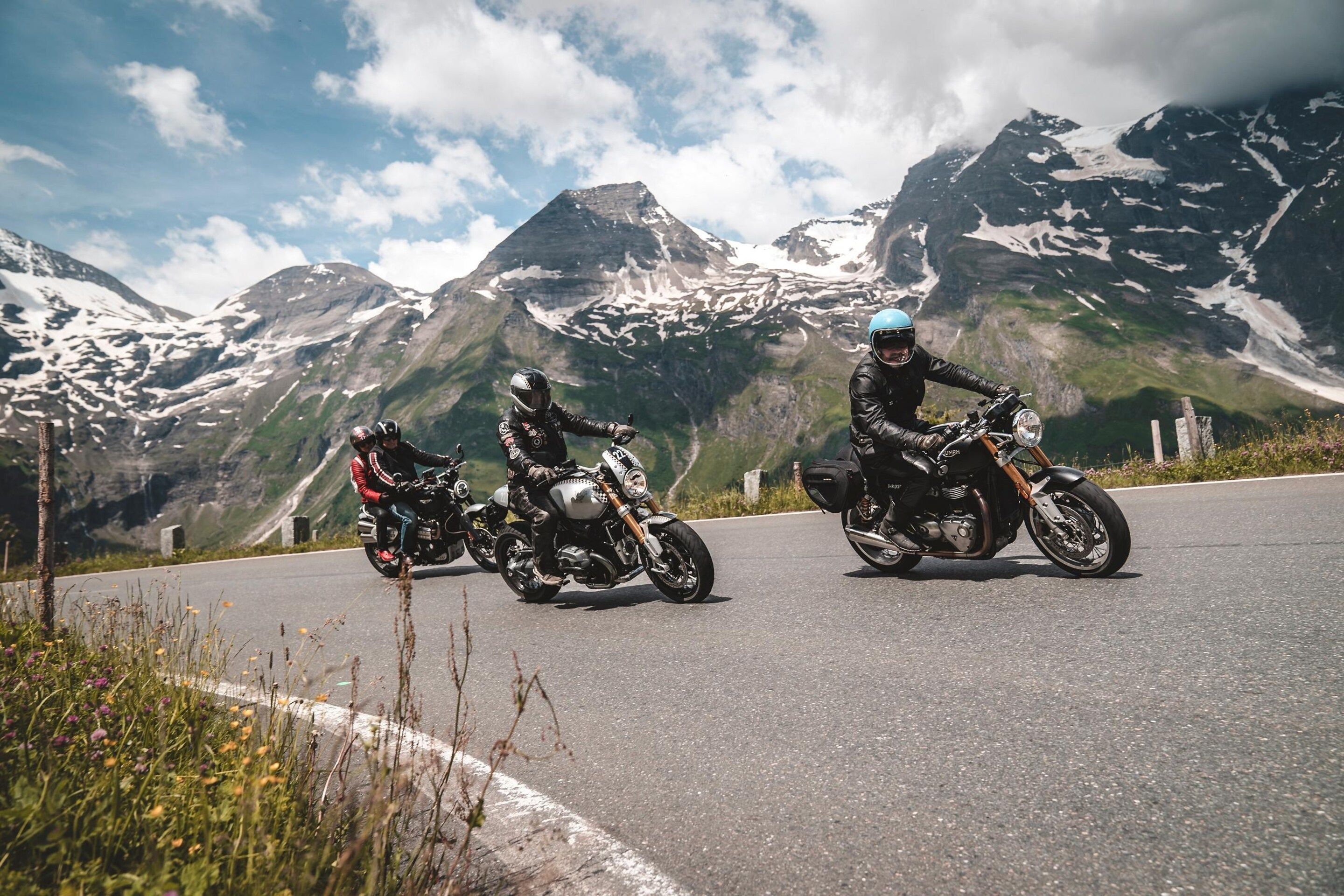 Two motorcyclists on a road with a mountainous backdrop.