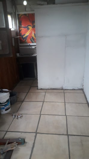 Ein Zimmer mit Fliesenboden, einer weißen Tür und einem farbenfrohen, abstrakten Gemälde an der Wand.