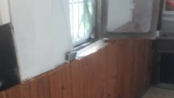 A room with a wooden panel wall, a tiled floor, and a window with metal bars.