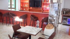 Un espace bar avec des tabourets hauts, une table en marbre et un grand vase.