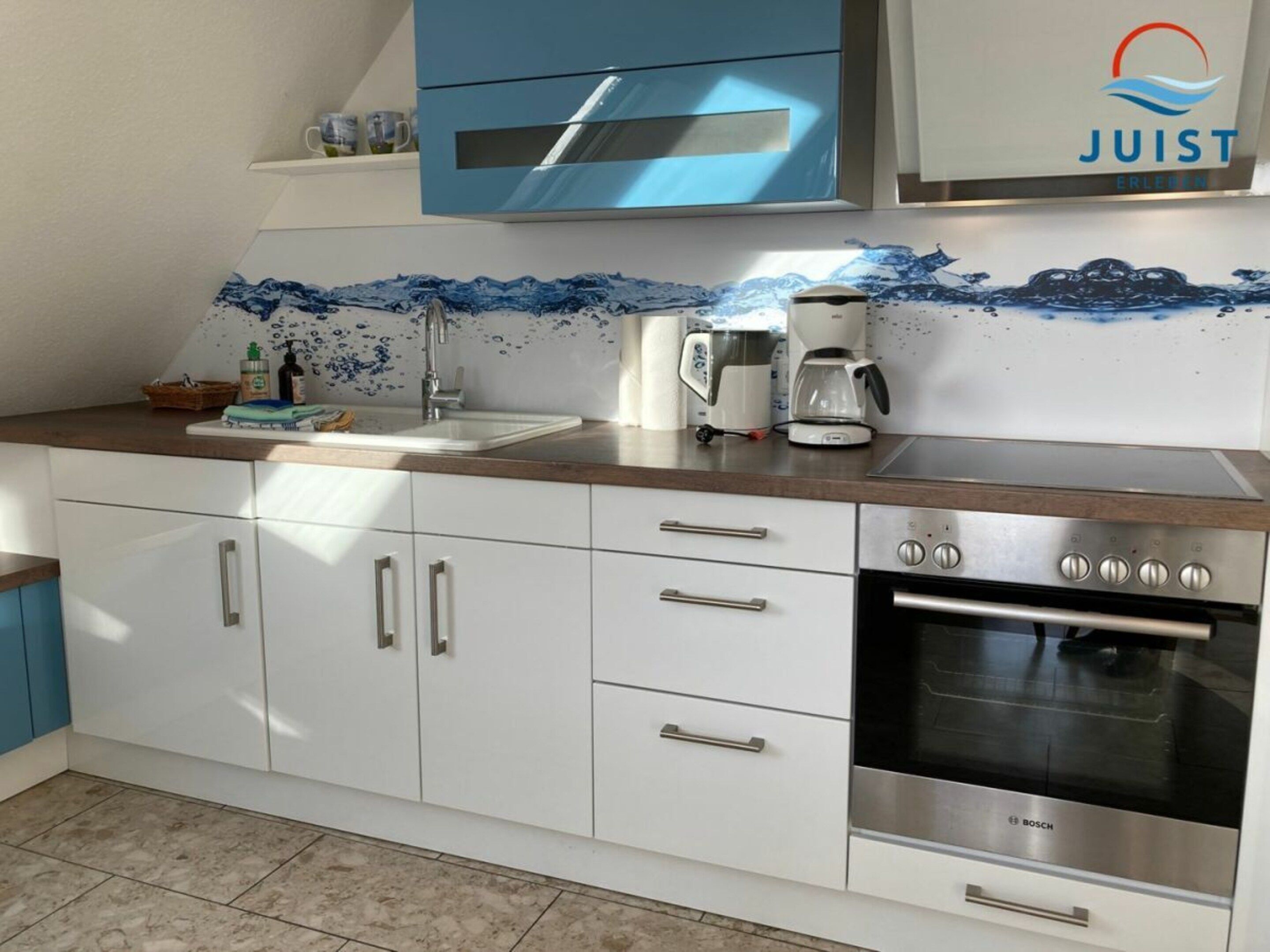 A modern kitchen with white cabinets, a Bosch oven, and a coffee maker on the counter.