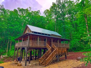 A wooden cabin with a balcony and a staircase, surrounded by dense forest. - Treehouse cabin Cozy 2-bedroom in Dobson, NC (Dobson)