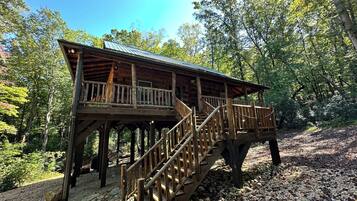 A wooden cabin with a balcony and a staircase.